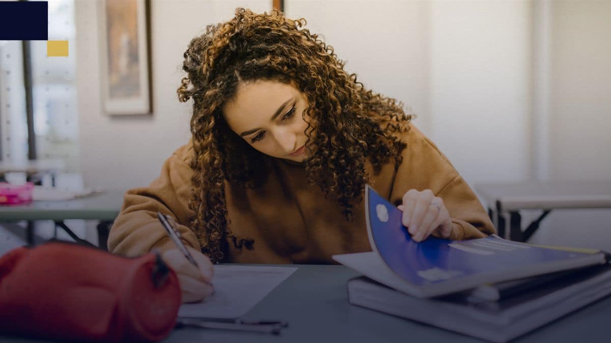 Estudiante redactando agradecimientos de tesis en un aula universitaria