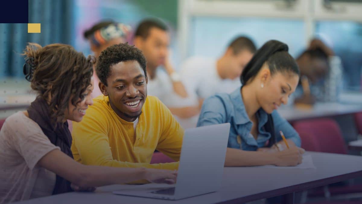 Estudiantes colaborando en clase con laptop y cuadernos para redactar textos argumentativos usando conectores