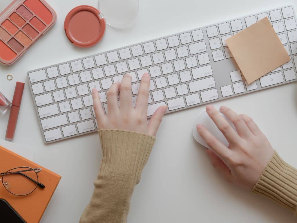 Agradecimientos de tesis escritos en computadora Manos escribiendo agradecimientos de tesis en computadora con escritorio organizado.