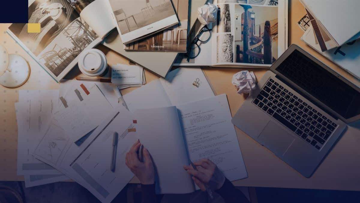 Mesa de trabajo con laptop, documentos y libros para elaborar el diseño metodológico de una investigación