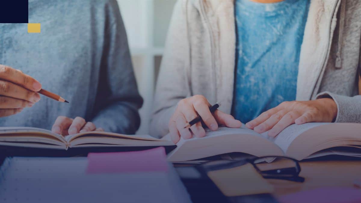 Estudiantes analizando libros y tomando apuntes para aplicar técnicas de investigación académica