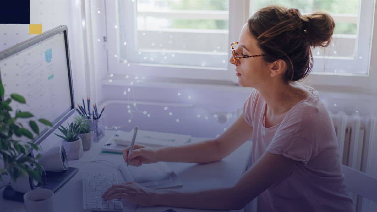 Persona redactando en computadora y tomando notas para mejorar la continuidad textual en textos académicos