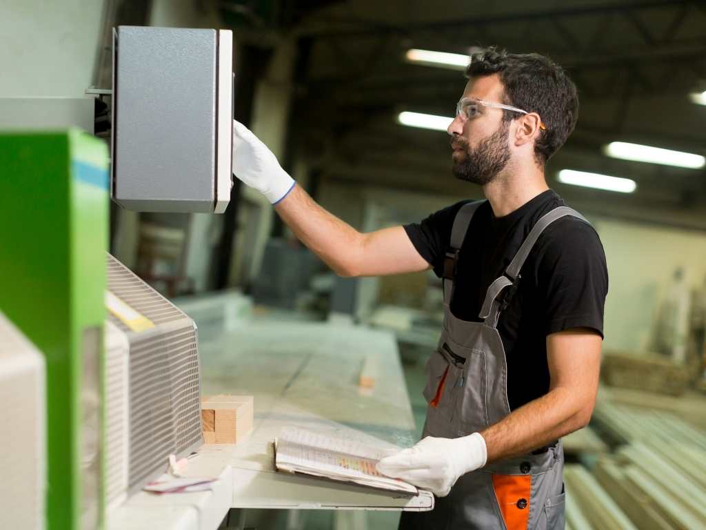 Procesos industriales: control y registro de datos para optimización en Ingeniería Industrial Operario de planta industrial utilizando maquinaria automatizada y registrando datos en una libreta, enfocado en la mejora y control de procesos productivos.