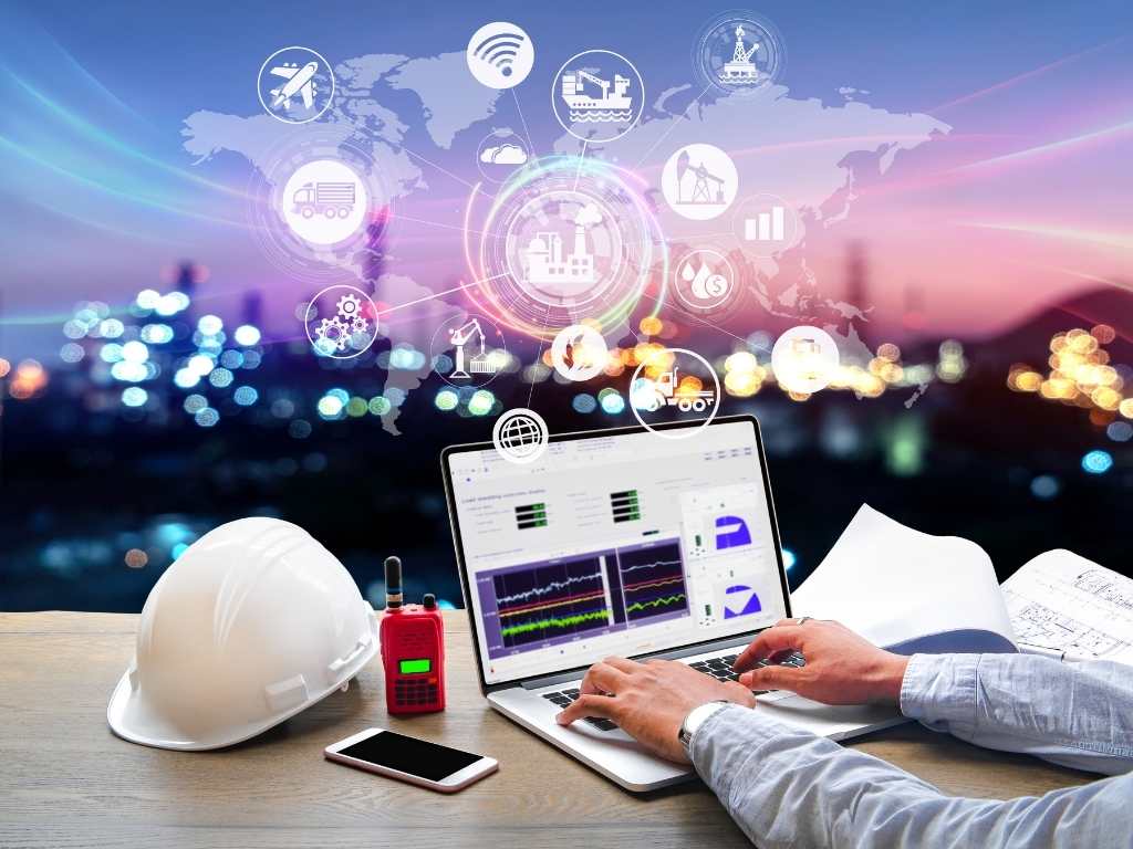 Ingeniería Industrial: análisis digital de procesos y datos para tesis y proyectos académicos Ingeniero industrial analizando datos y gráficos en laptop, con casco de seguridad, radio y planos sobre el escritorio, y gráficos de procesos industriales superpuestos.