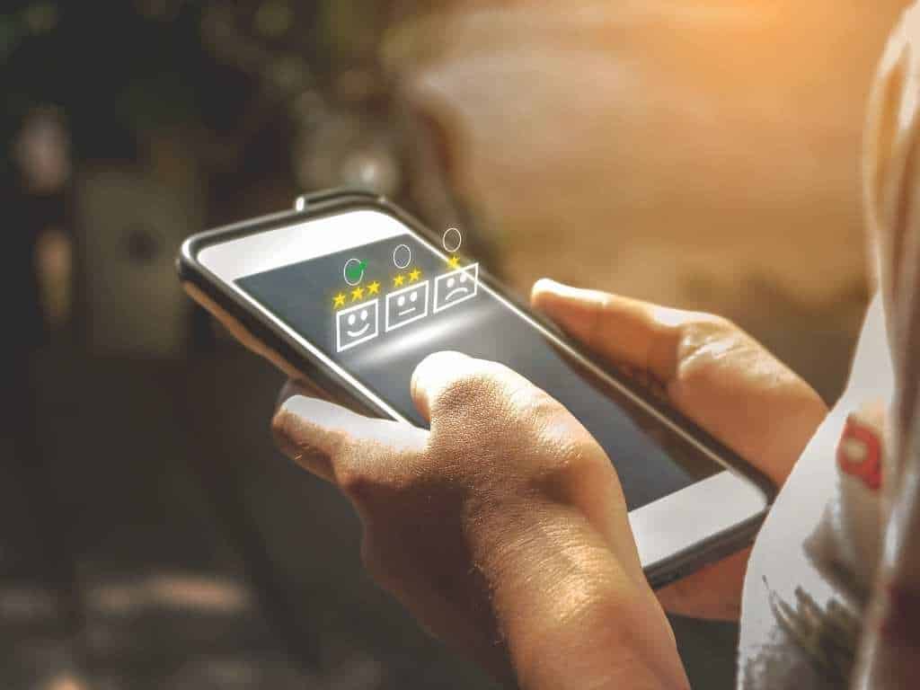 Encuesta digital: usuario seleccionando respuestas en una evaluación de satisfacción Persona usando una tablet para responder una encuesta digital de satisfacción, seleccionando opciones con iconos de caritas y estrellas.