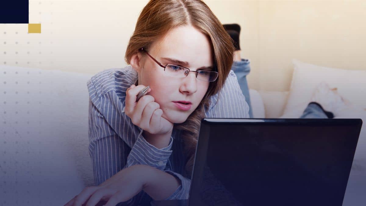 Joven estudiante recostada usando laptop, investigando y redactando resultados de un estudio correlacional desde casa.
