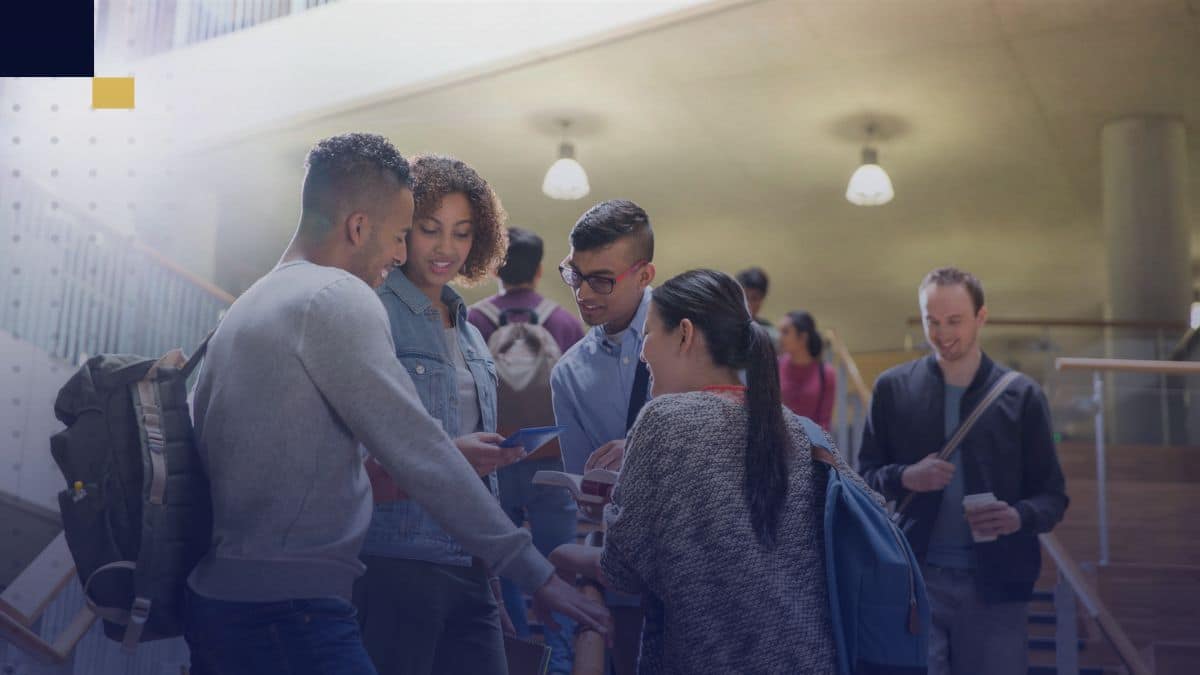 Estudiantes universitarios conversando y compartiendo información en un pasillo, ilustrando la propagación de la muestra en el muestreo bola de nieve.