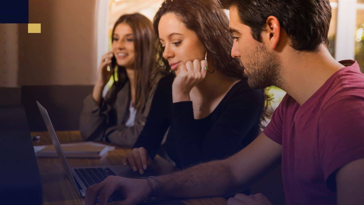 Grupo de estudiantes universitarios usando laptop y cuadernos, discutiendo y organizando variables para un proyecto de investigación.
