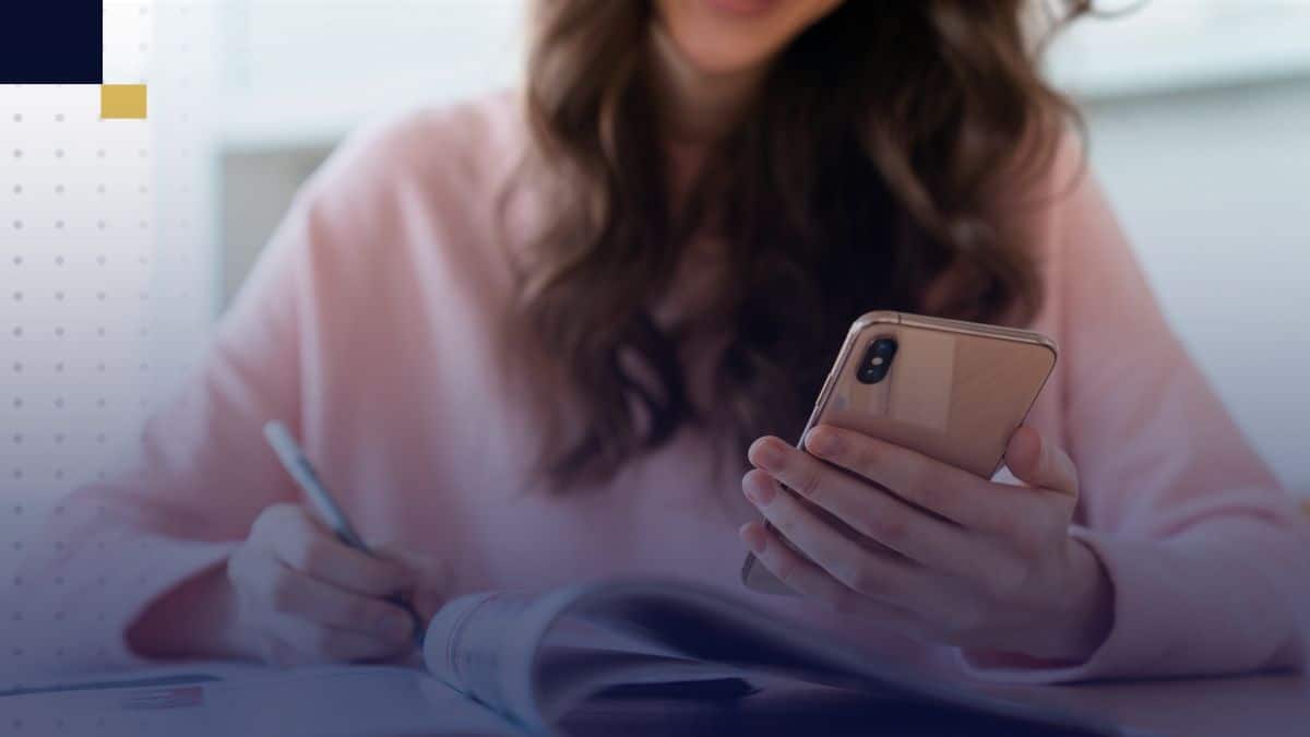 Estudiante universitaria revisando libros y tomando notas en laptop, comparando diferentes tipos de tesis para elegir el enfoque adecuado a su investigación.