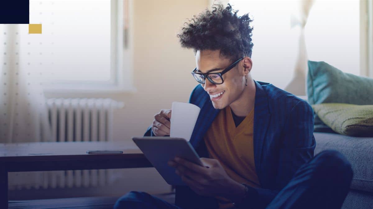 Estudiante universitario sentado en casa, tomando café y revisando ideas de temas para tesis en una tablet.