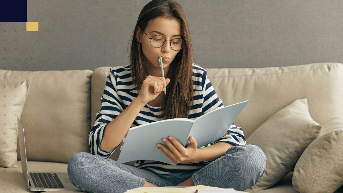 Estudiante analizando bibliografía y tomando notas para redactar el marco teórico de su tesis