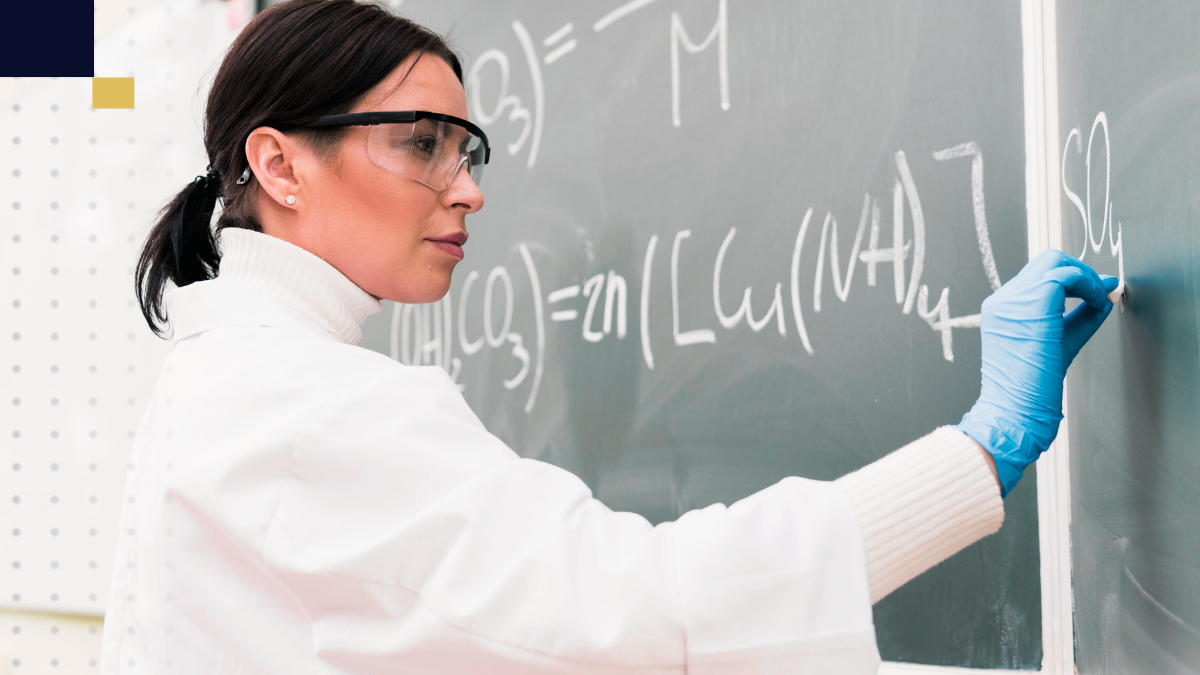 Investigadora resolviendo ecuaciones químicas en pizarra durante proyecto de ciencias exactas